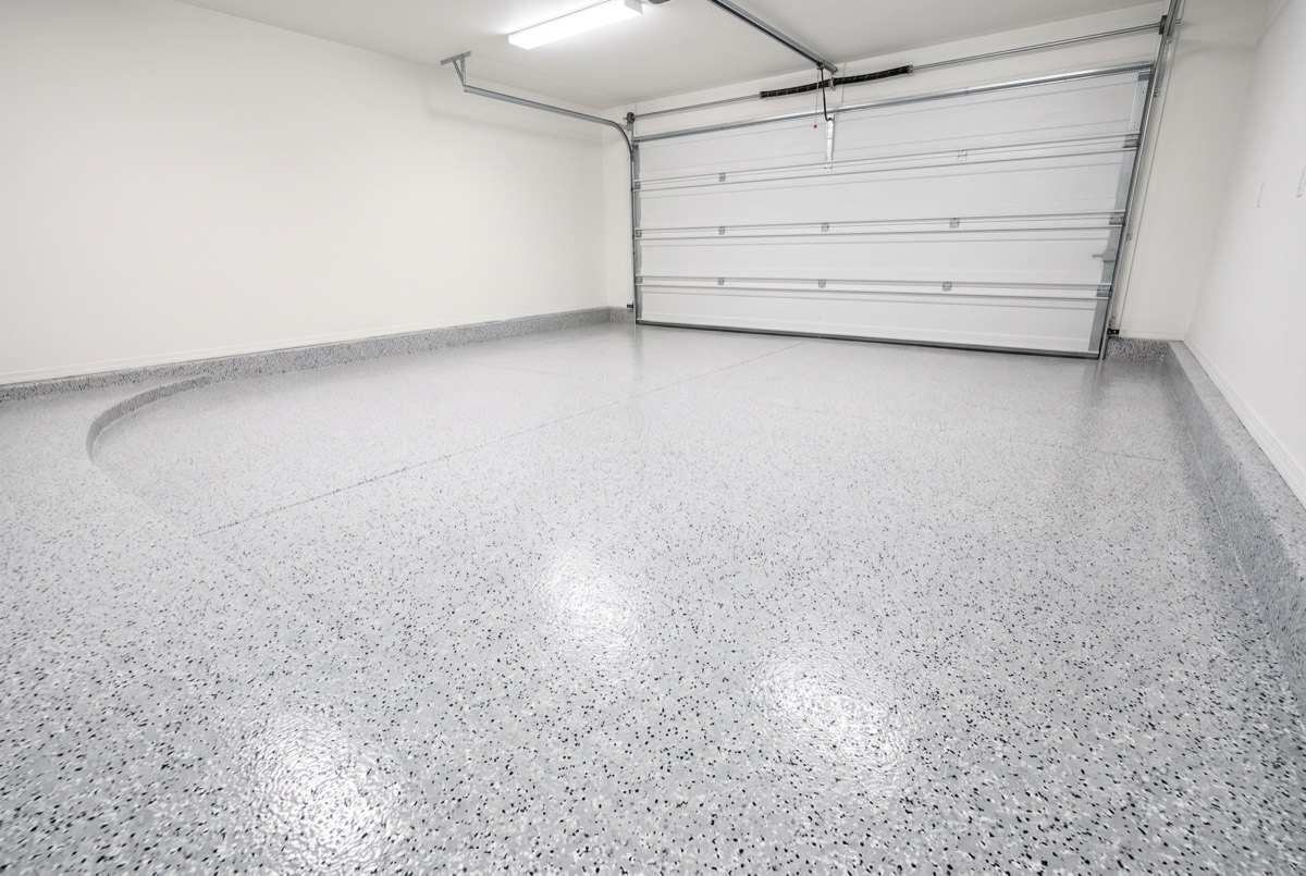 Illustration of an empty two-car garage with a glossy light gray and white flake epoxy floor and coved edge